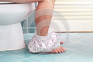 Man sitting on a toilet seat in the bathroom