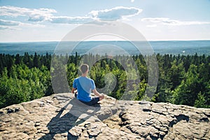 Man sitting on the top of the mountain in meditation session in Lotus Posture, padmasana, practicing pranayama