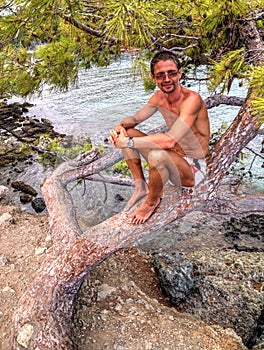 Man sitting on tree - Phaselis bay - Ã‡amyuva, Kemer, coast and beaches of Turkey