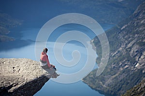 Man sitting on trolltunga rock in norway