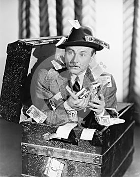 Man sitting in a trunk with money in his hands