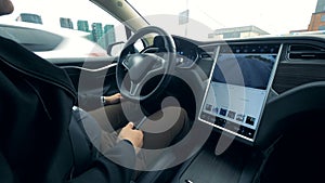 A man is sitting in a vehicle which is being automatically driven