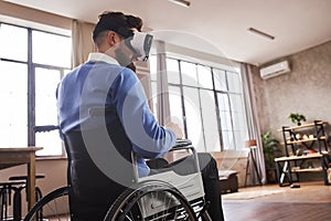 Man sitting in a wheelchair and wearing a VR headset at home