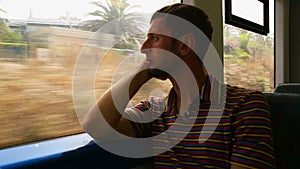 Man sitting by window and looking at changing landscape from fast moving train