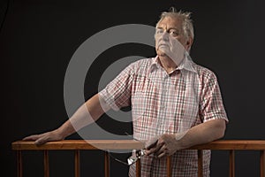 Man in sixties on trial, standing behind wooden dock