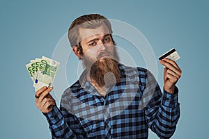 Muž skeptický výberu plastický úver karta alebo peniaze hotovosť bankovky 
