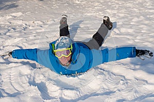 Man with ski goggles is having fun at winter. Smiling man is lyi