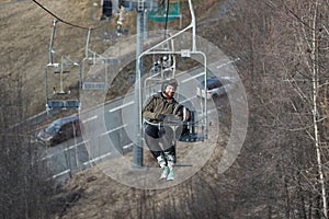 Man on ski lift at a ski resort with lack of snow