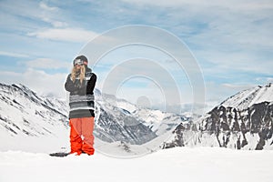 Man with ski mask stands on background of snowy mountains.