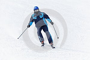 Man in ski suit glides downhill on skis