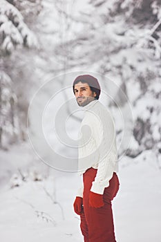 Man in ski suit and sweater in snowy forest during winter vacations outdoors