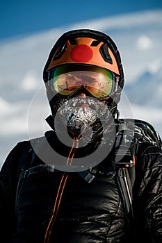 man skier with beard wearing black jacket and ski helmet and goggle