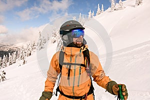 man skier with beard wearing yellow jacket and ski helmet and goggles
