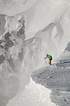 Man skier with climbing equipment fixed himself with a safety rope and holds a shovel