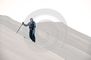 man skier in stands and looks to the side against a background of snow