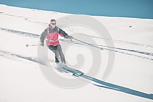 Man skiing off piste on snowy slope in the italian Alps, with bright sunny day of winter season. Powder snow with ski tracks. Tone