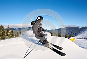 Man skiing on prepared slope with fresh snow. Snow gun machine making artificial snowfall. Magic nature on background.