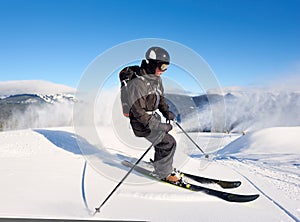 Man skiing on prepared slope with fresh snow. Snow gun machine making artificial snowfall. Magic nature on background.