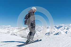 A man with skis stands high in the mountains enjoying the scenery. Go downhill skiing, extreme relaxation