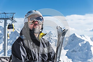 A man with skis stands high in the mountains enjoying the scenery. Go downhill skiing, extreme relaxation