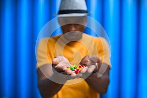 Man with skittles standing against blue background, black lives matter concept.