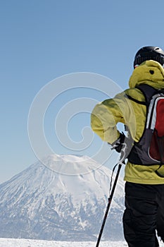 Man in skiwear standing looking at snow-capped mountain