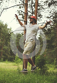 Man slacklining walking and balancing on a rope, slackline in forest