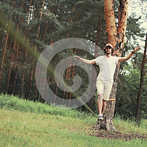 Man slacklining walking and balancing on a rope, slackline in forest