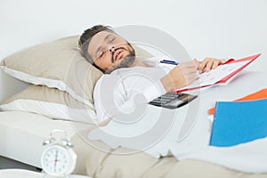 Man sleeping on bed with finaces notes