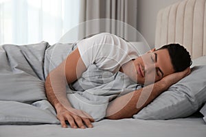 Man sleeping in bed with grey linens at home photo