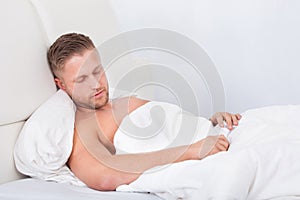 Man sleeping in bed propped up against the pillows
