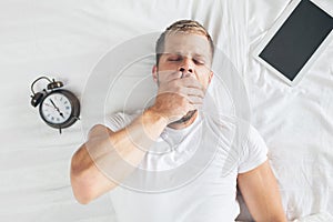 Man sleeping on bed after using his digital tablet