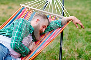 The man is sleeping on a hammock.