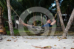 Man Sleeping on a Hammock or a net near on a Beach