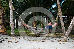 Man Sleeping on a Hammock or a net near on a Beach