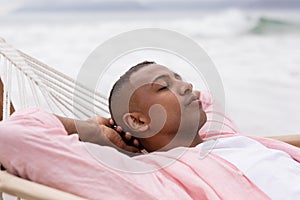 Man sleeping with hands behind head on a hammock