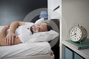 Man sleeping in his bedroom with alarm clock in foreground