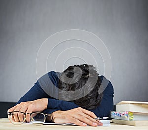 Man sleeping on work wooden desk, study hard and tired concept