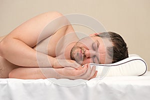 The man sleeps on an orthopedic pillow on his side. The Correct Memory Foam Pillow.