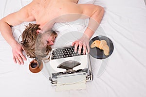 Man sleepy lay bedclothes while work. Writer used old fashioned typewriter. Author tousled hair fall asleep while write
