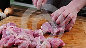 Man slicing pork meat on a table, working process closeup. Kitchen, knife.