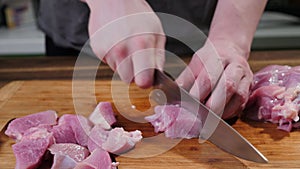 Man slicing pork meat on a table, working process closeup. Kitchen, knife.