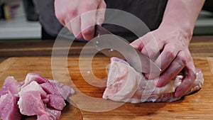 Man slicing pork meat on a table, working process closeup. Kitchen, knife.