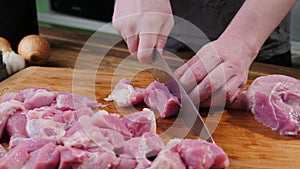 Man slicing pork meat on a table, working process closeup. Kitchen, knife.