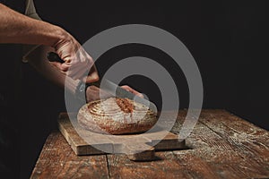 Man slicing tasty fresh bread.