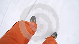 Man is sliding on skates on frozen ice lake. Top view. Male legs in black skates and bright pants are skating on frozen