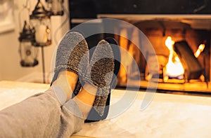 Man in slippers relaxing with his feet up with a fireplace in the background. photo