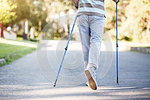 Man slowly walking in park while using sprinter sticks