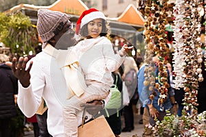 Man with small girl who pointing to Christmas decoration at fair