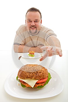 Man with small hamburger reaching for a bigger one